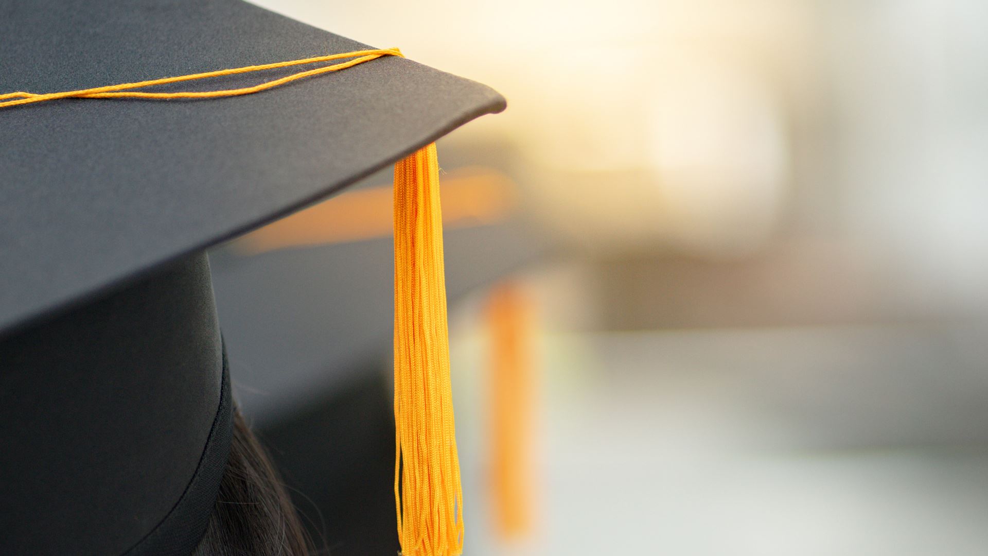 Young happy Asian woman university graduate in graduation gown and cap in the college campus